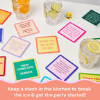 Drinks On Me’s Protein Shake Coaster features a witty saying and bright colors, shown on a white table with drinks and citrus slices. A smiling emoji hovers above, while pink text suggests it as a perfect hostess gift for parties.